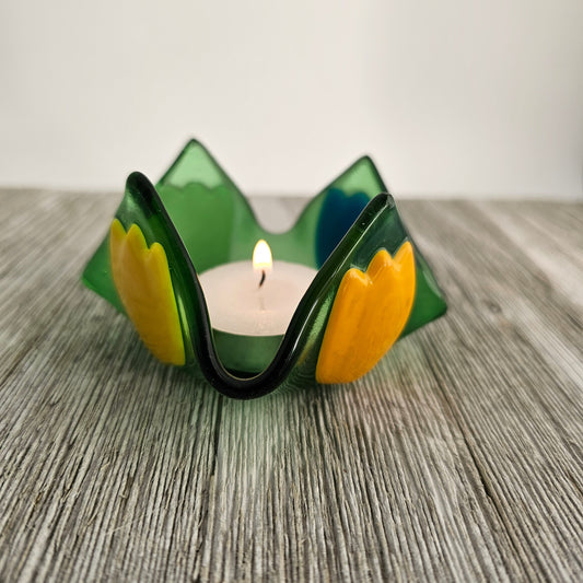 A green glass dish that comes to 4 points and has tulip of different color on each side.