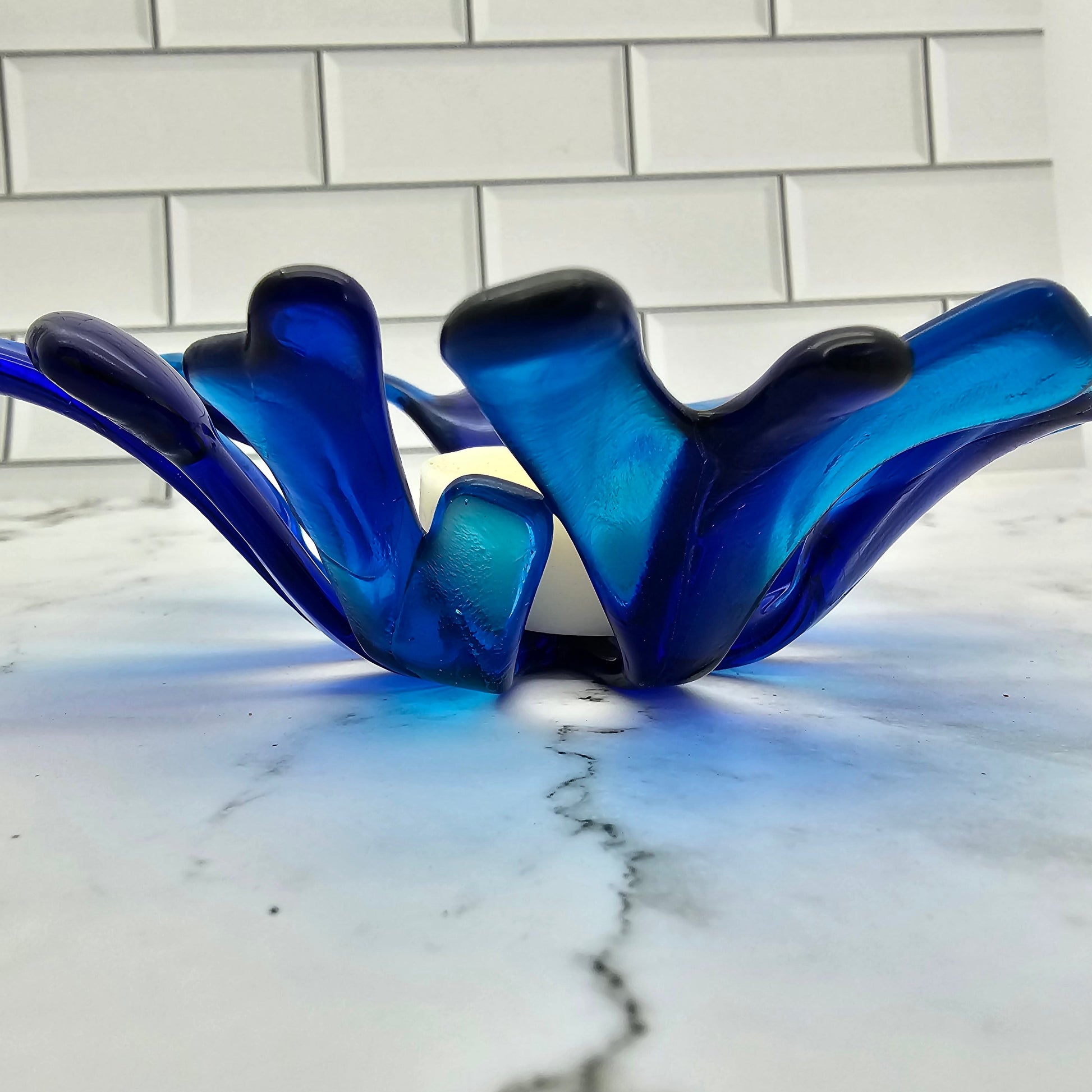 Coral style bowl in varied shades of blue on a white marble surface. 