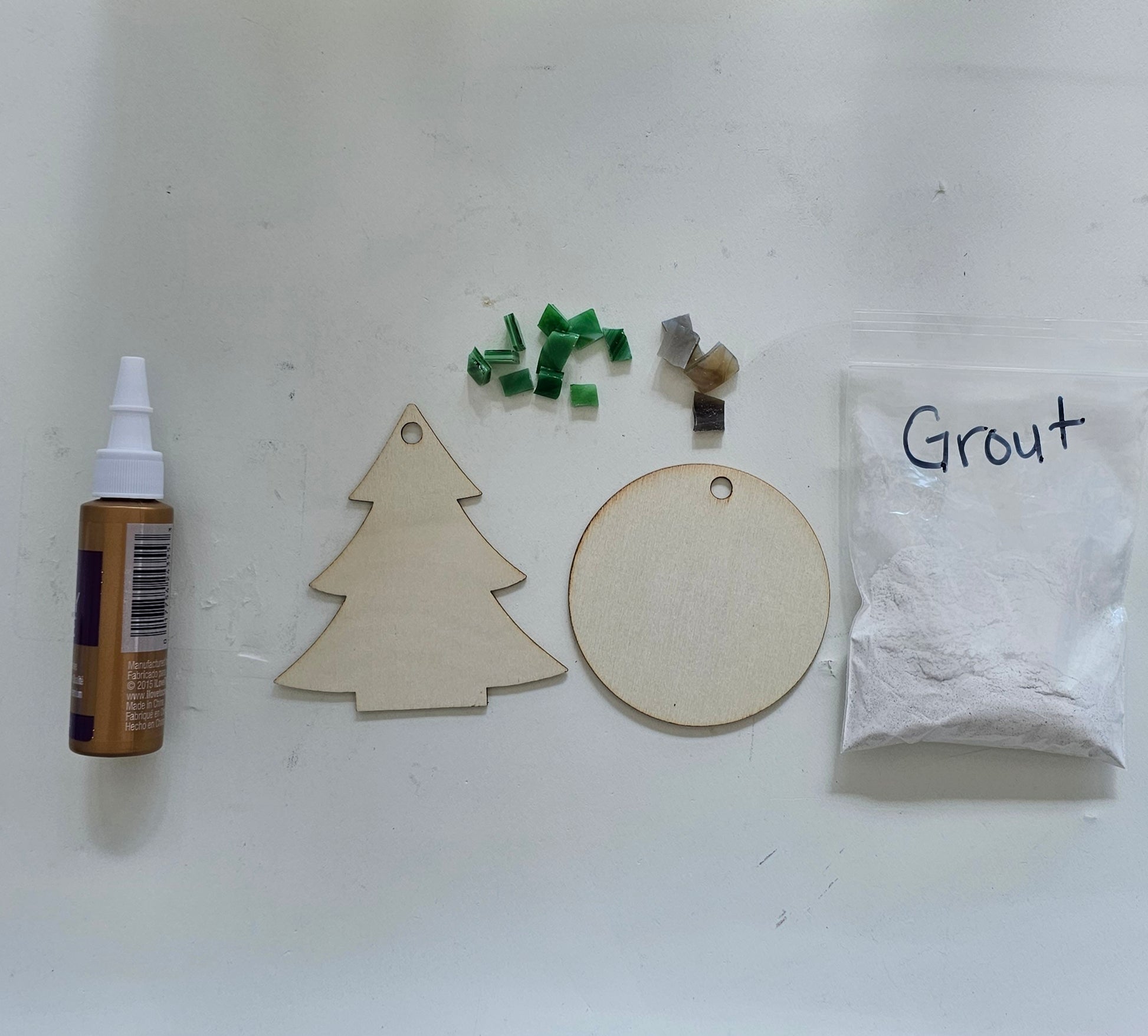 Wooden Christmas tree and circle shapes with grout and a grout container on a white background