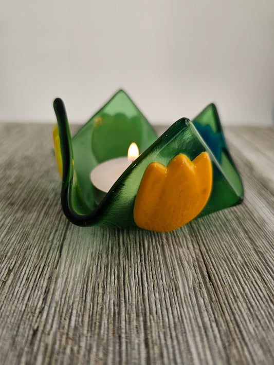 A green glass dish that comes to 4 points and has tulip of different color on each side.