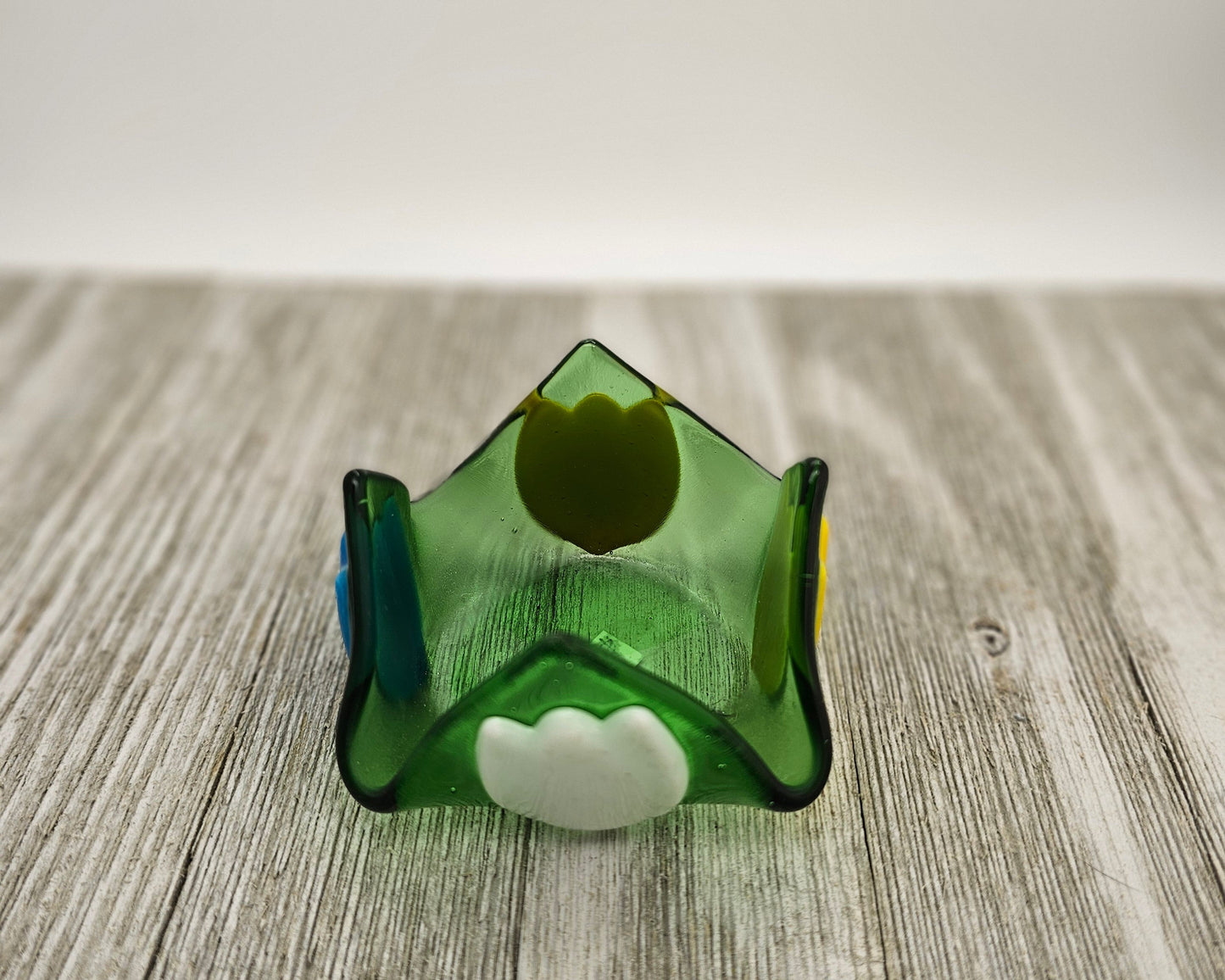 A green glass dish that comes to 4 points and has tulip of different color on each side.
