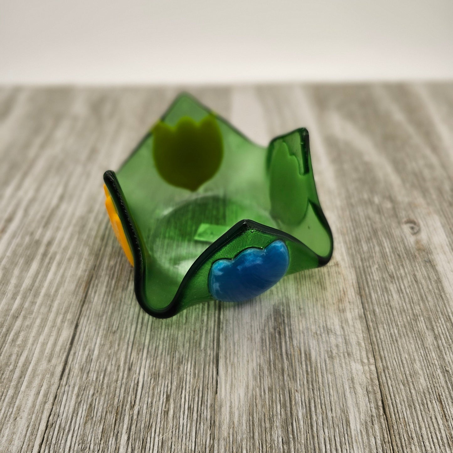 A green glass dish that comes to 4 points and has tulip of different color on each side.