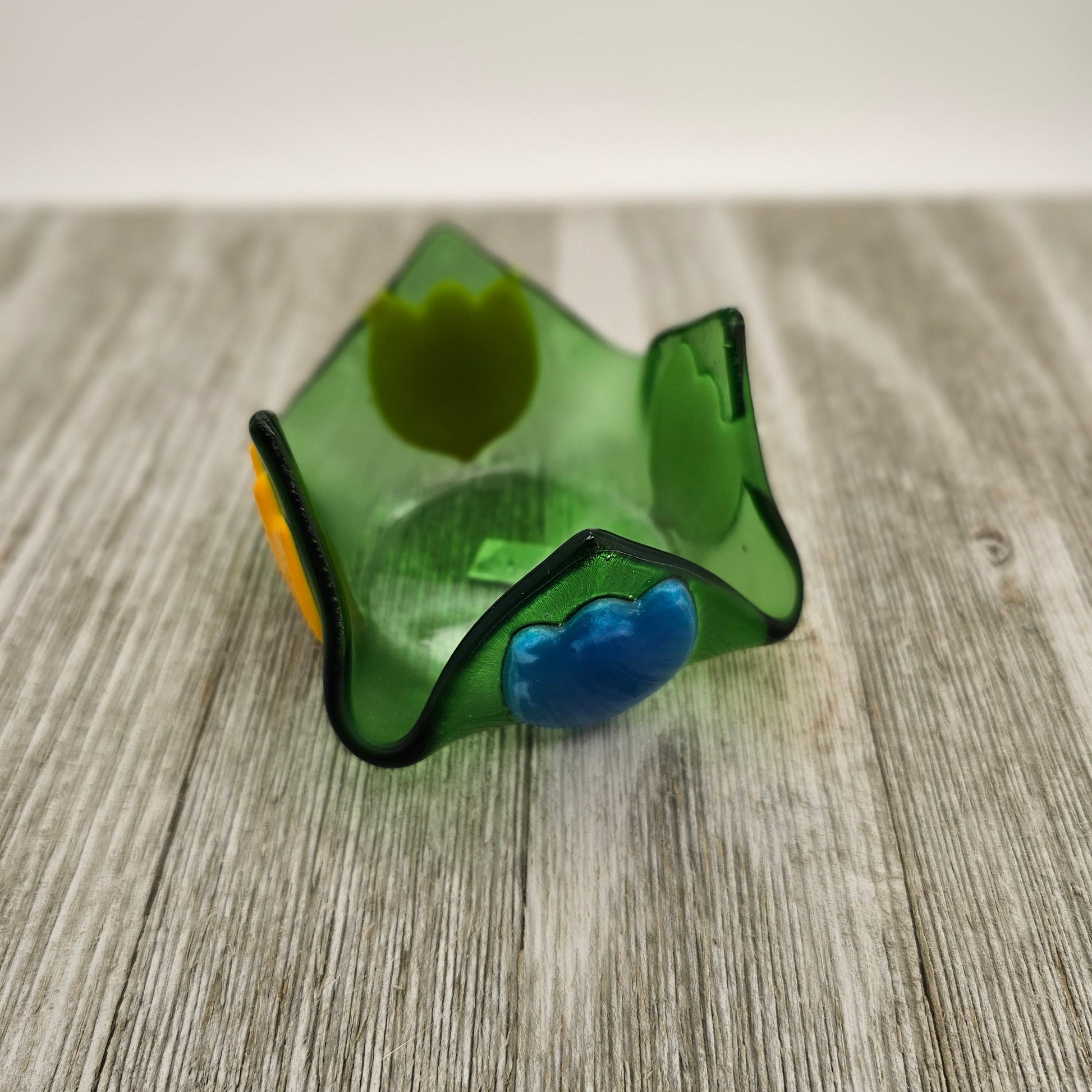 A green glass dish that comes to 4 points and has tulip of different color on each side.