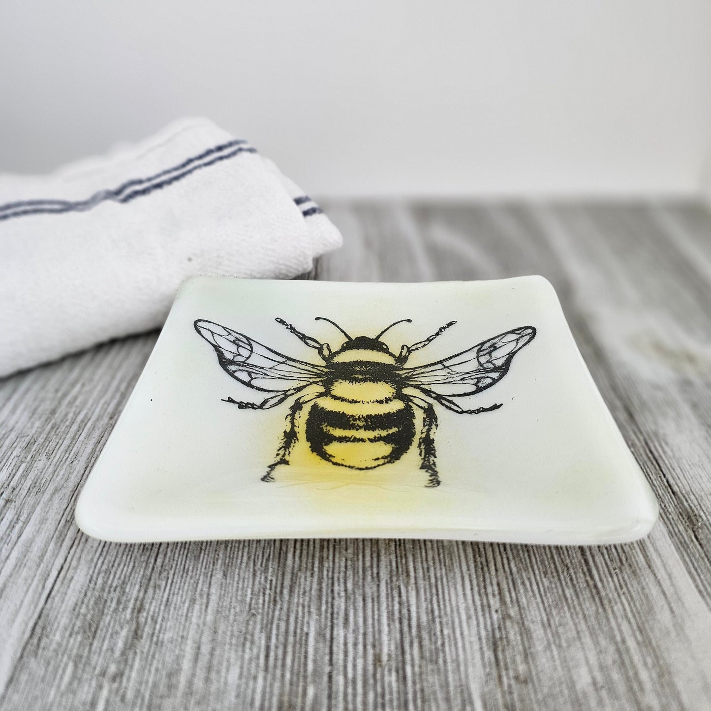 handcrafted dish features a screen-printed bumblebee that has been fused into the glass. The bee’s details add a touch of nature-inspired beauty to this functional piece. trinket dish, a jewelry holder, or simply displayed
