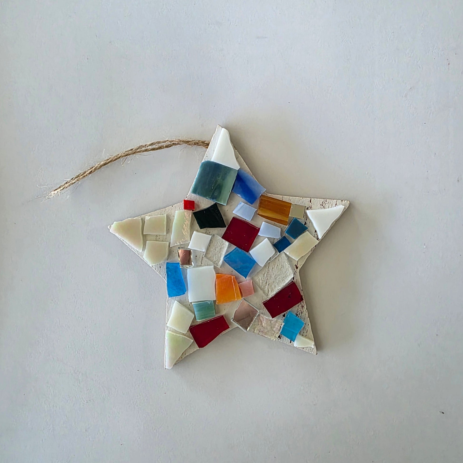 Star-shaped mosaic ornament with colorful tiles on a white background