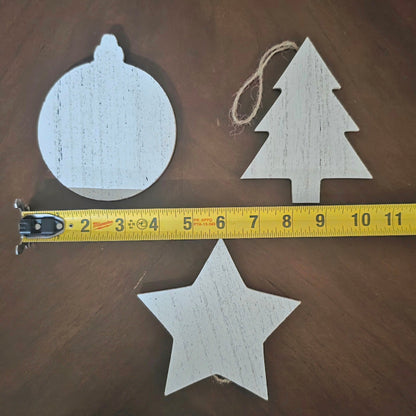 Wooden Christmas ornaments (sphere, tree, star) with a measuring tape on a wooden surface.  4" larger ornaments.