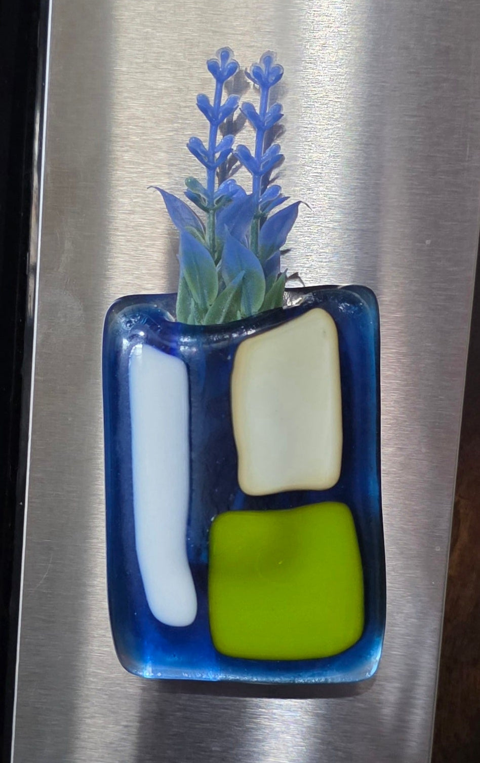 Decorative vase magnet with silk flowers on a silver fridge.
