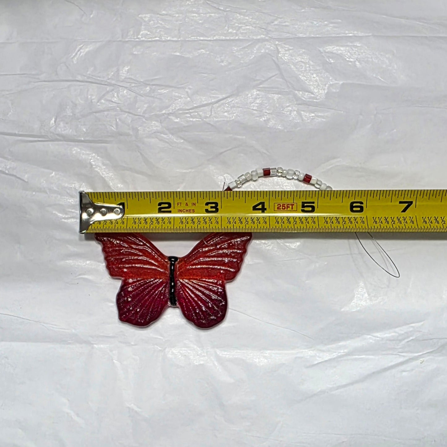 Red and orange butterfly hanging ornament, being measured at 3.5 in wide and has a beaded hanger.