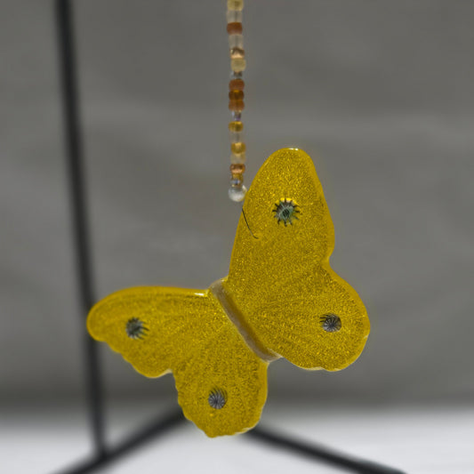 Yellow butterfly hanging on a beaded wire with a white background.