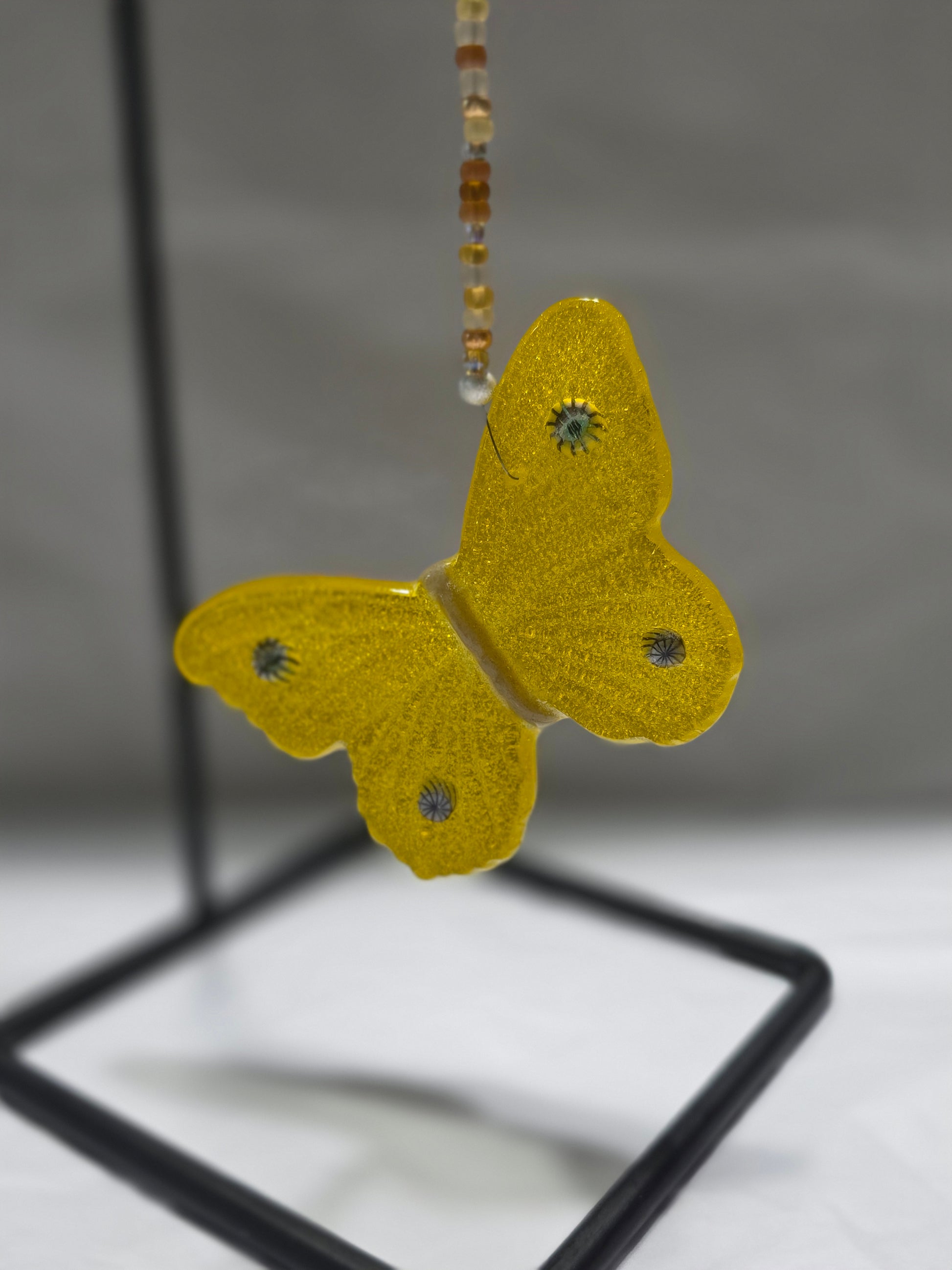Yellow butterfly hanging from a beaded wire