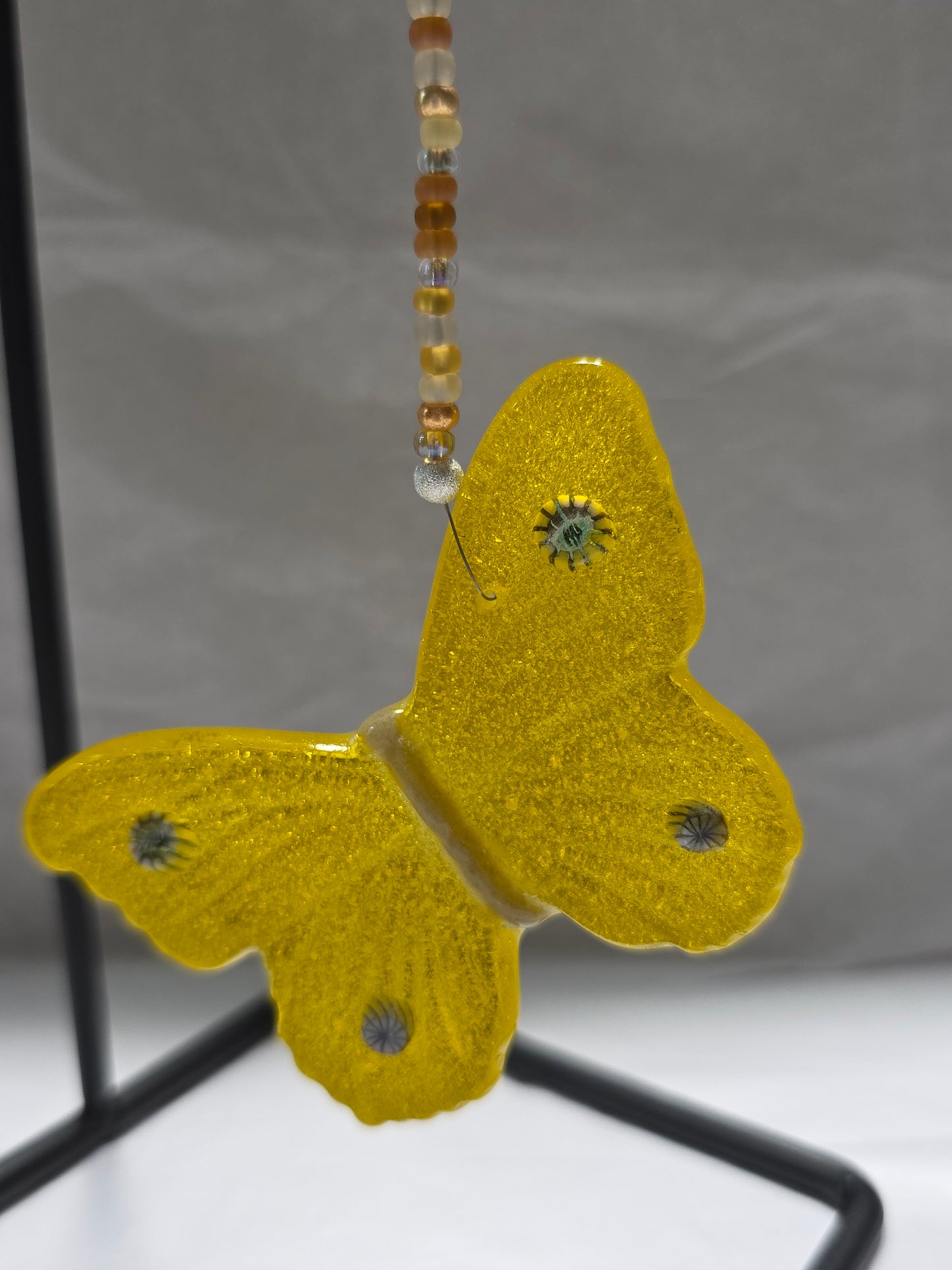 Yellow butterfly hanging from a beaded wire. 