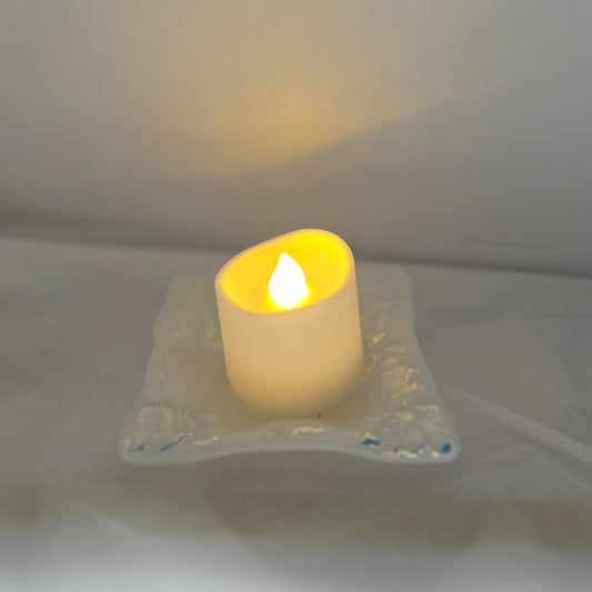 White dish with sparkle design that is displayed as a candle holder, displays a battery operated candle. 