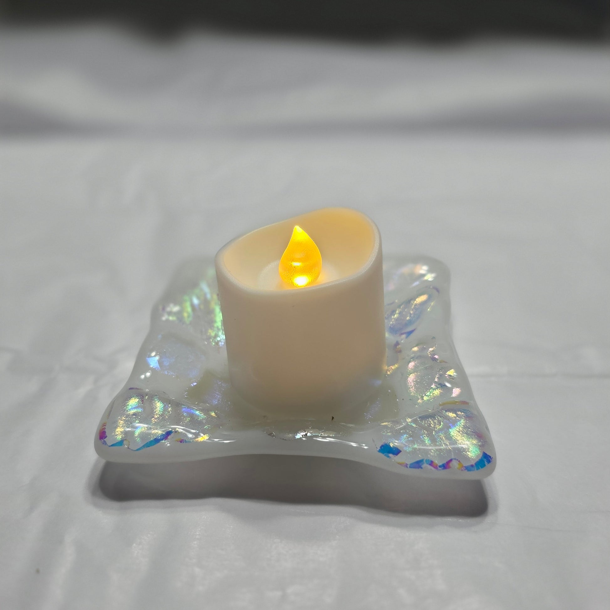 White dish with sparkle design that is displayed as a candle holder, displays a battery operated candle. 