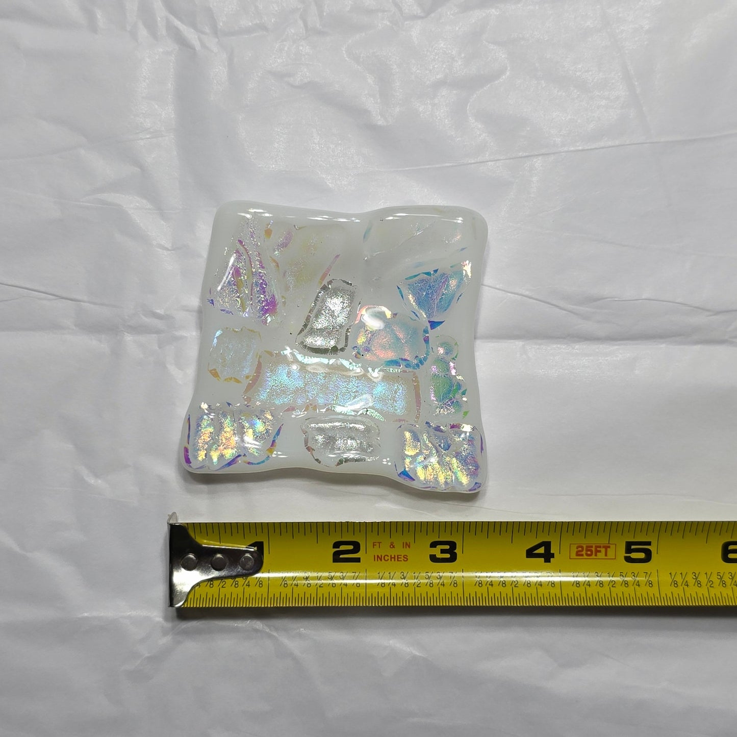 Iridescent square dish with a measuring tape on a white background