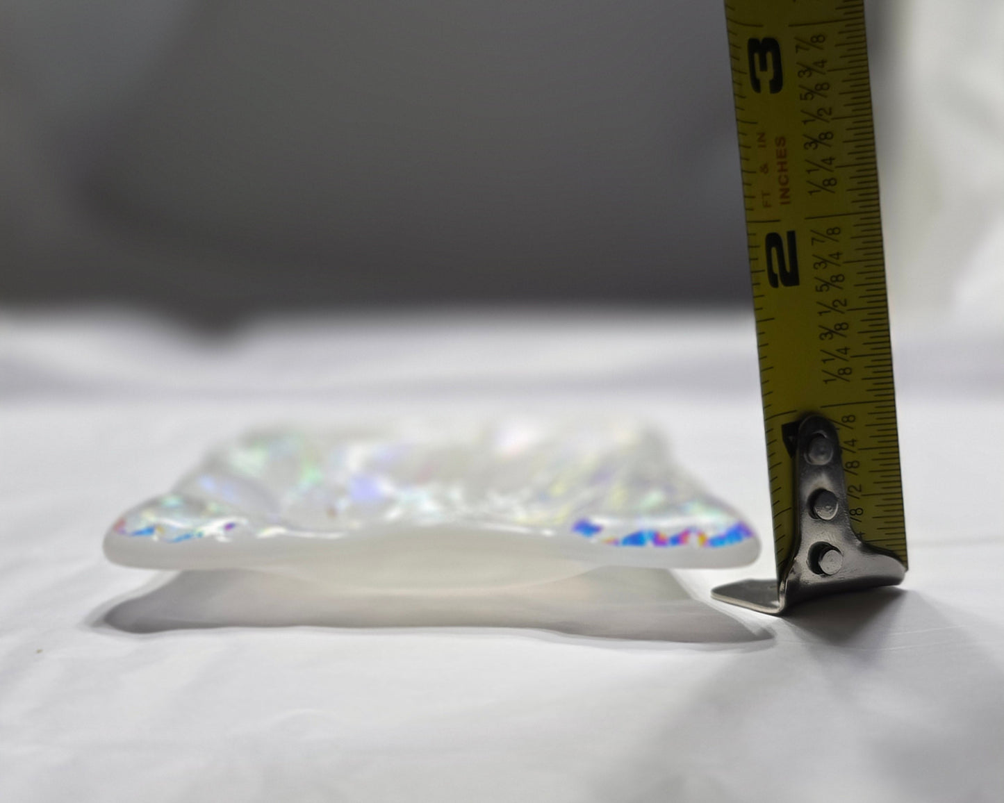 Measuring tape on a crystal pendant against a white background