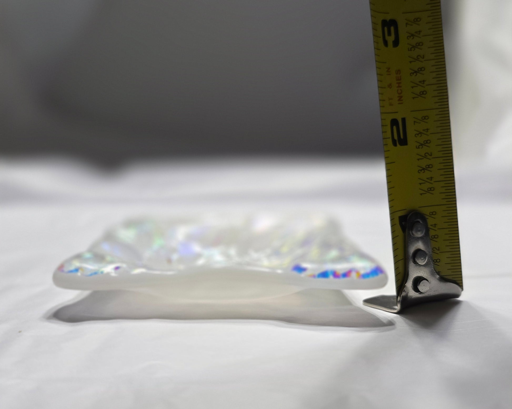 Measuring tape on a crystal pendant against a white background
