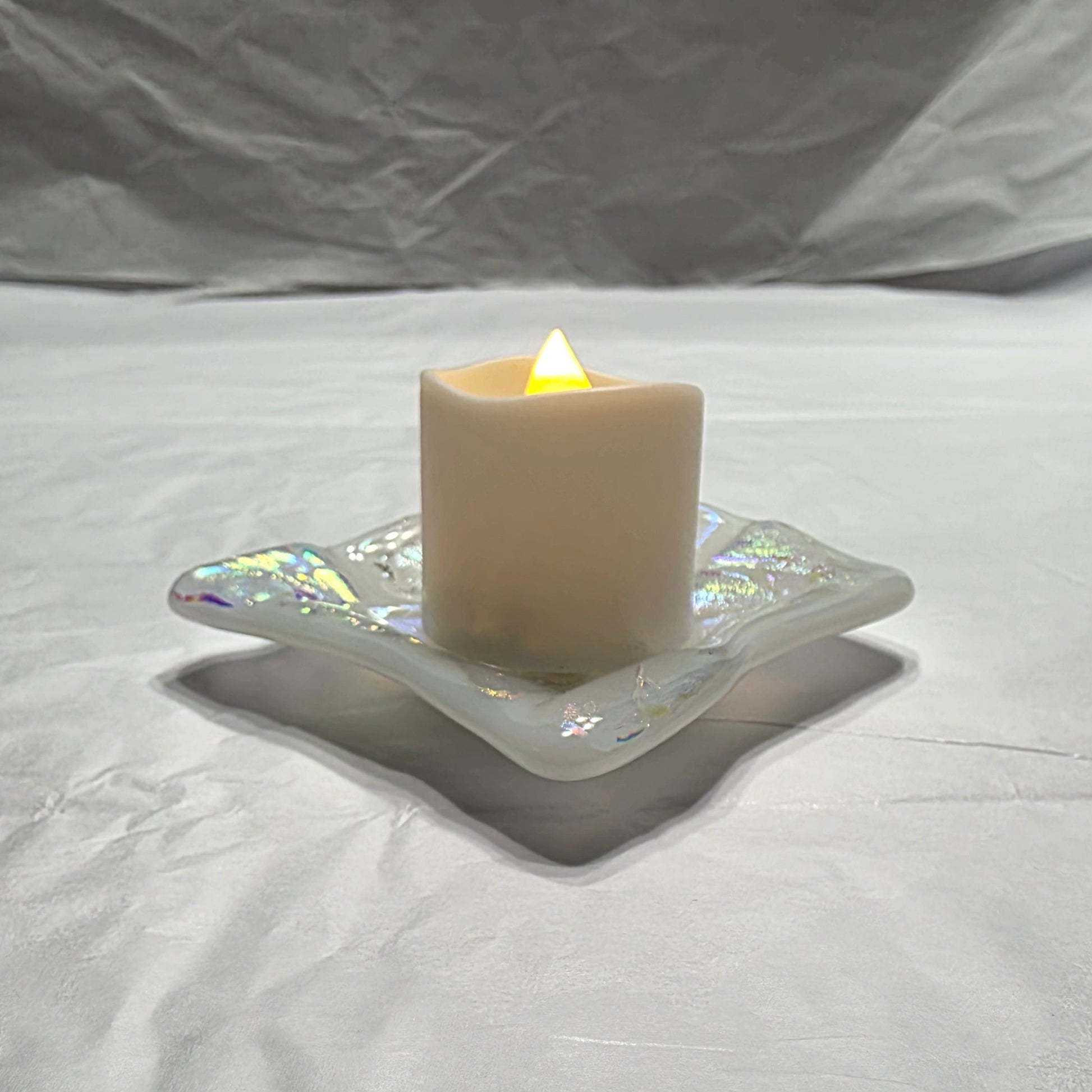 Candle in a decorative holder on a textured white surface