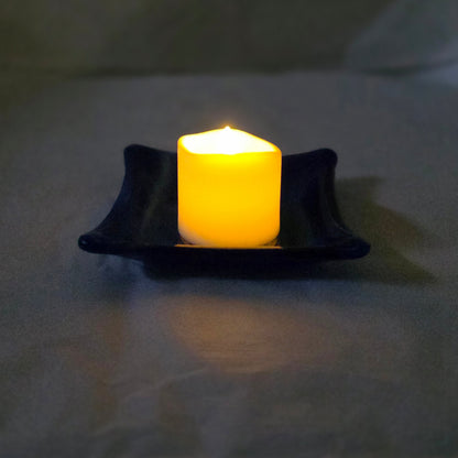 A little blue and white dish with a candle on it. Implying dish can be used as a candle holder.