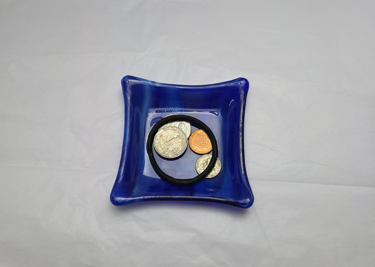 Various blue and white streaky colored little dish.  Dish is on a white surface. The little dish has coins and a hair tie indicating can be used as a trinket or ring dish.