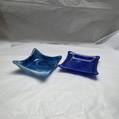 Two little dishes that are streaky white and blue. Dishes are sitting on a white surface.