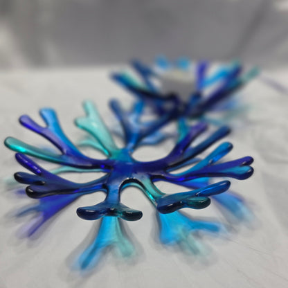 A various shade of blue glass bowl in a coral reef design. The blue coral bowl is sitting on a white surface.
